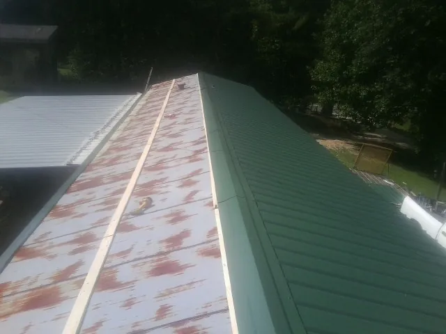 Old rusted panels beside newly installed green metal roofing — Wind Damage Roof Repair by Roofing Brothers in Salisbury